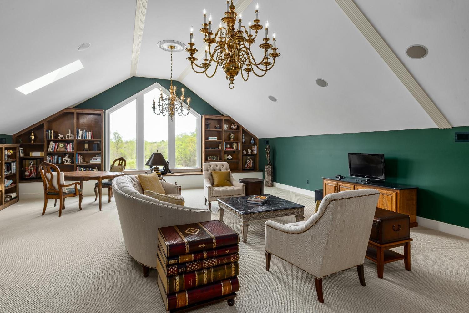 finished attic living room in custom home with built-in shelves and chandelier by Carolina Signature Custom Homes Troutman NC