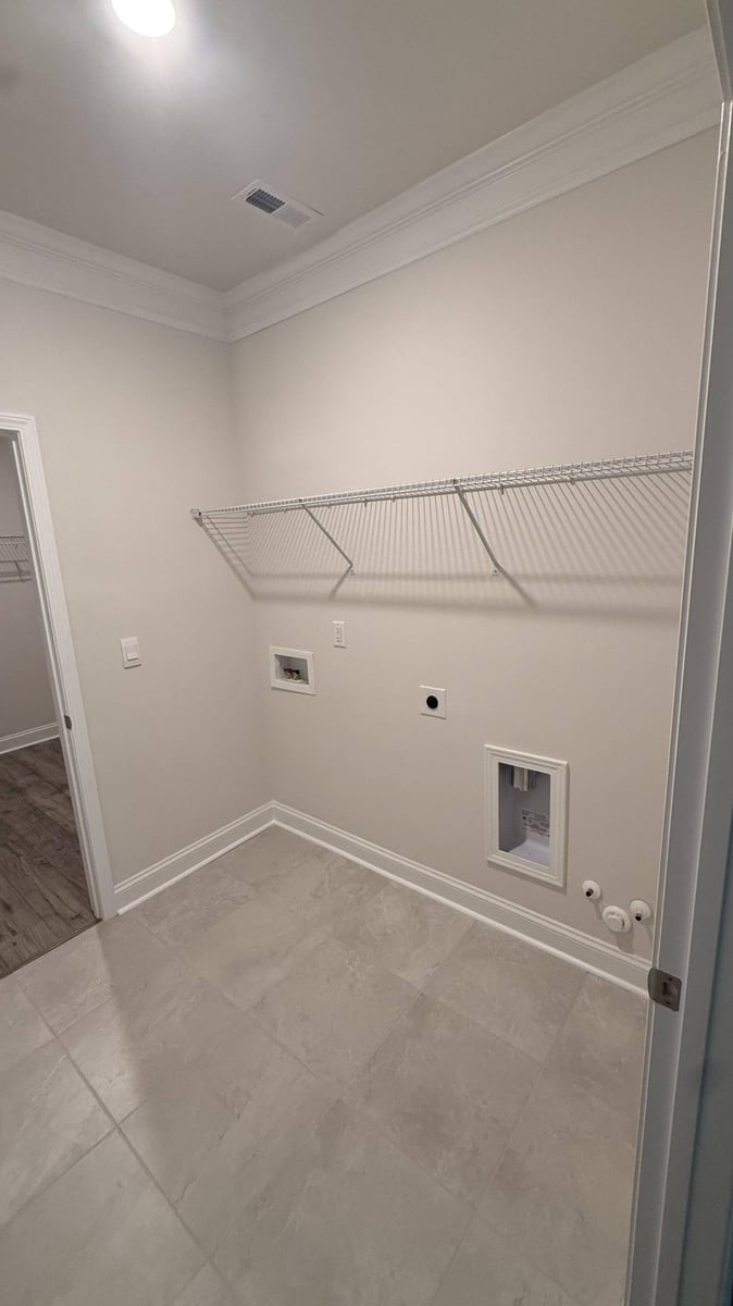 clean laundry space with crown molding and shelving in Troutman, NC by Carolina Signature Custom Homes-optimized