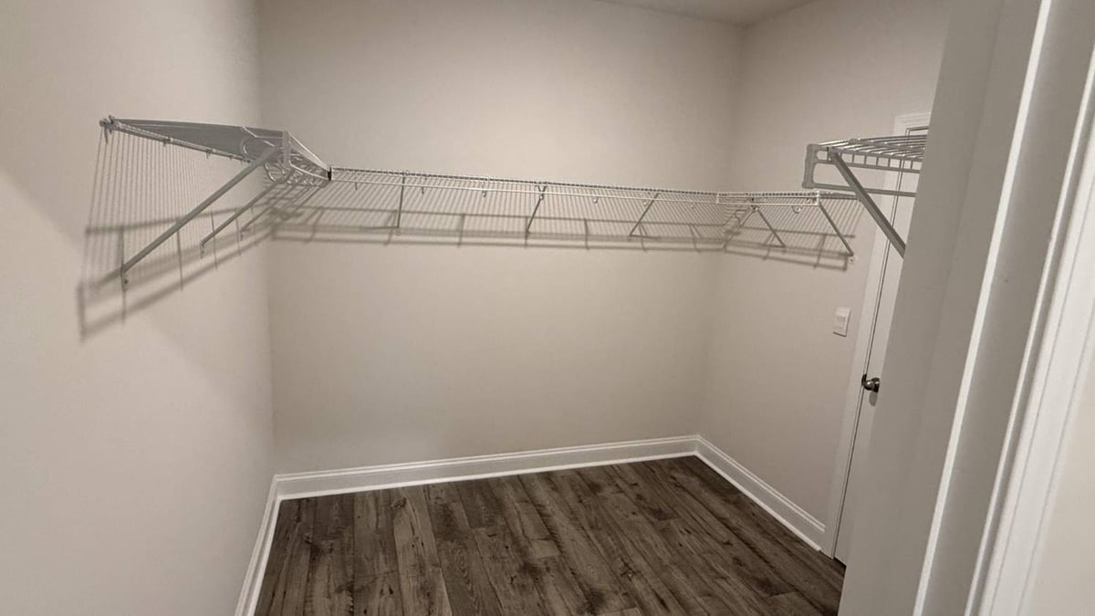 empty walk-in closet with metal rack shelving by Carolina Signature Custom Homes in Troutman, NC-optimized