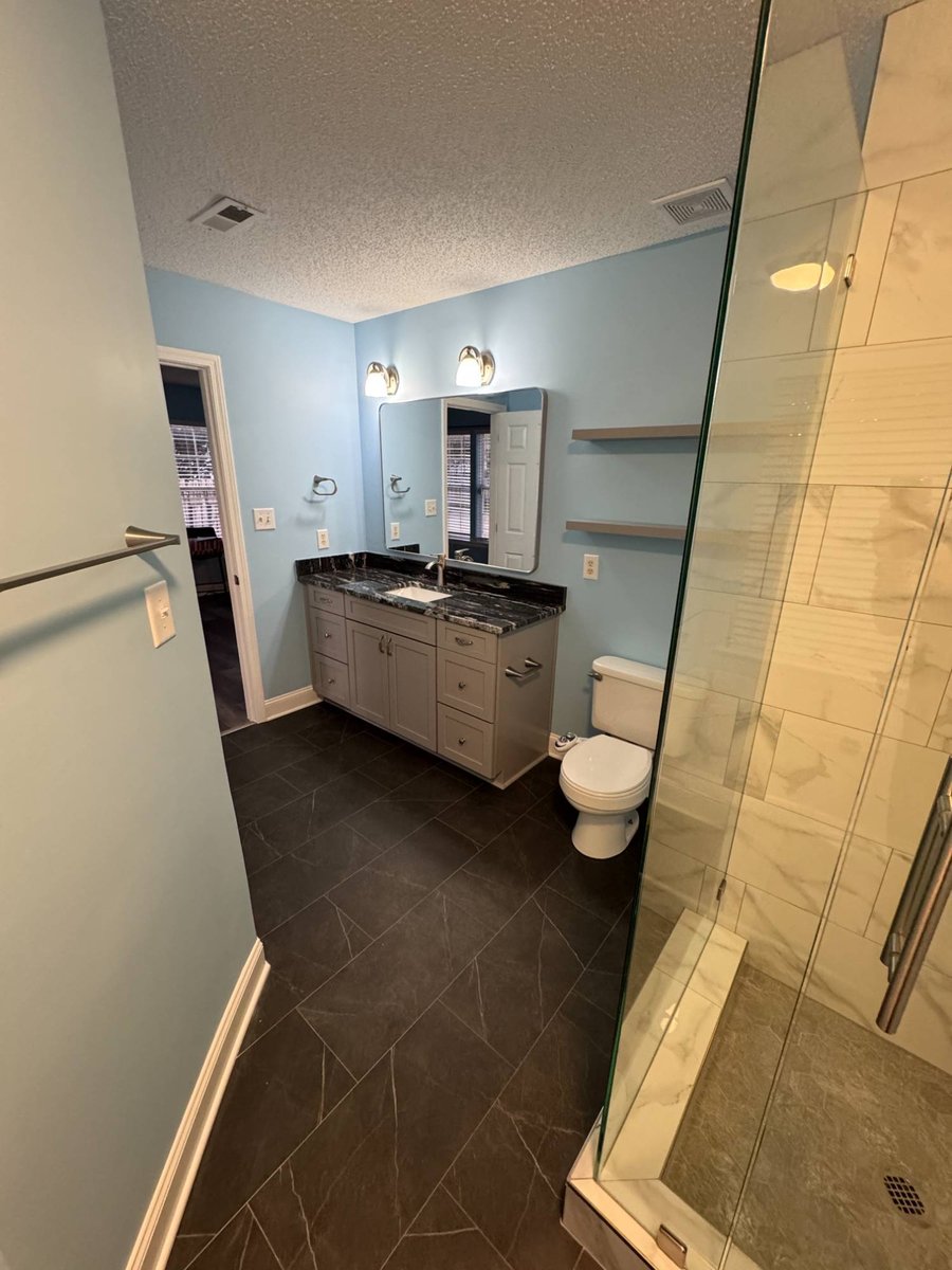 remodeled bathroom with tile flooring and glass enclosed shower by Carolina Signature Custom Homes in Aitken Charlotte NC-optimized