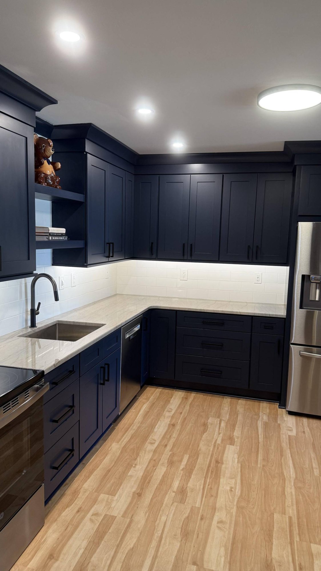 Corner kitchen remodel in Higgins, NC by Carolina Signature Custom Homes with navy cabinets, quartz countertops, and under-cabinet lighting Corner kitchen remodel in Higgins, NC by Carolina Signature Custom Homes with navy cabinets, quartz countertops, and under-cabinet lighting