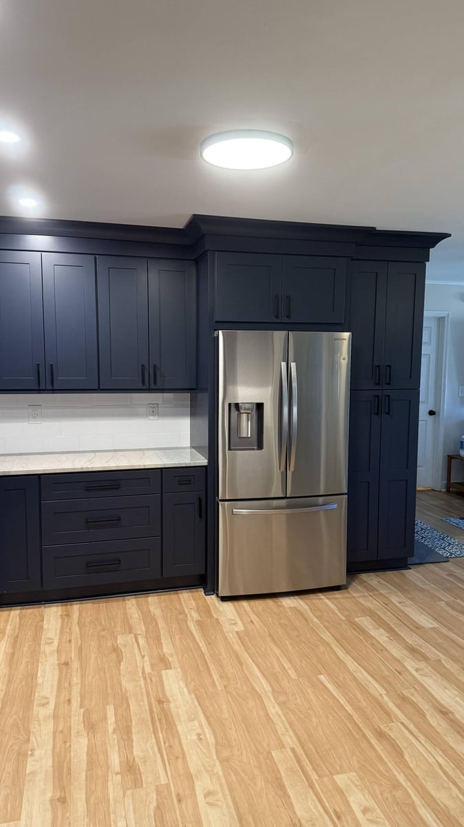 Refrigerator wall in remodeled kitchen by Carolina Signature Custom Homes in Higgins, NC with custom cabinetry and crown molding-optimized