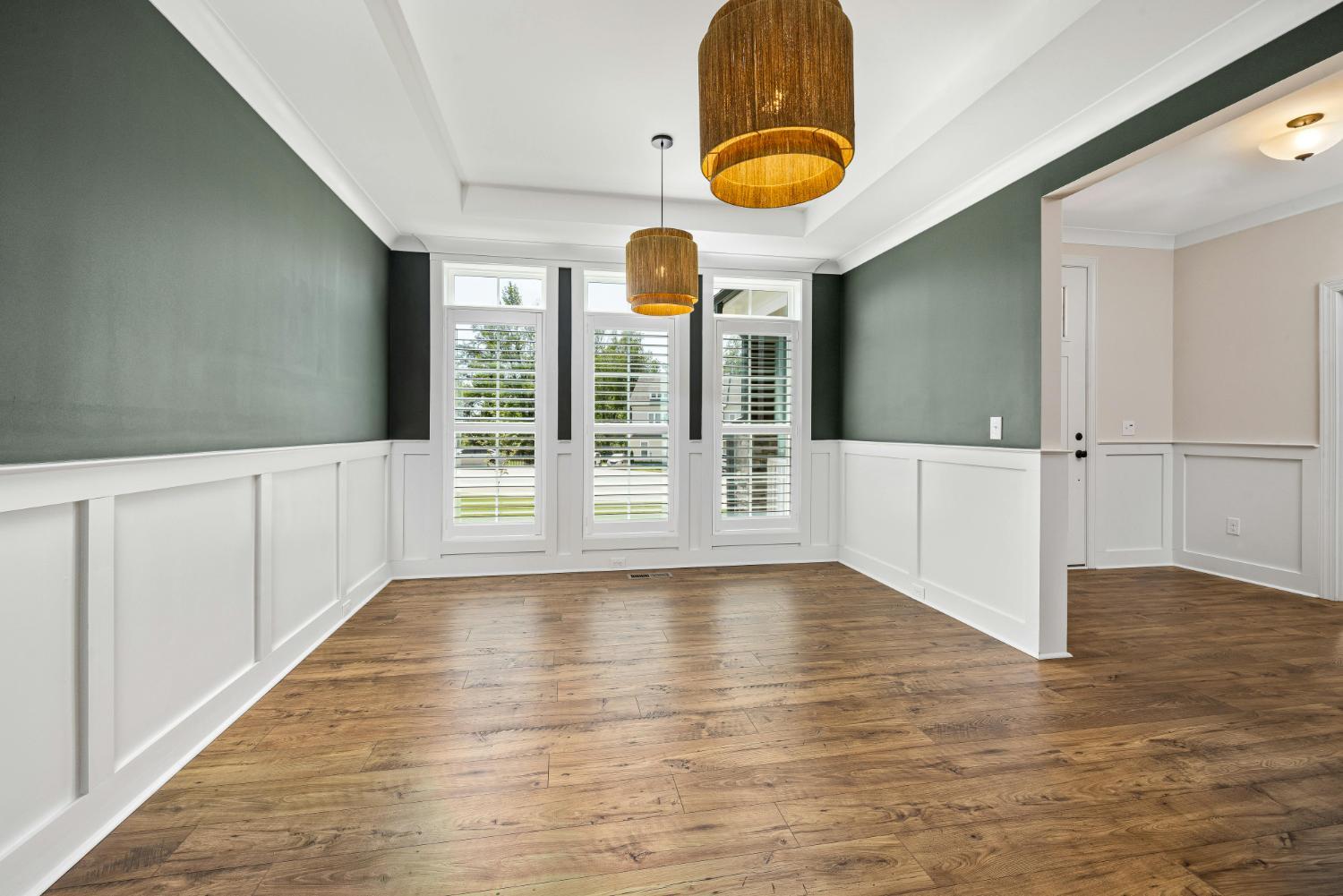 elegant dining room with green accent walls and wood flooring in Troutman NC custom home by Carolina Signature Custom Homes stoc-optimized