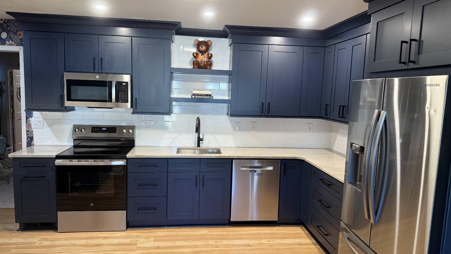Wide view of remodeled kitchen in Higgins, NC by Carolina Signature Custom Homes with navy cabinetry and integrated stainless ap-optimized